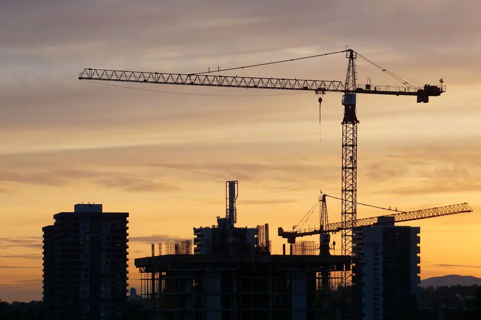 Tower cranes over a building under construction at sunset